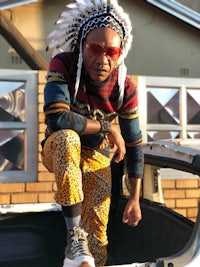 a man sitting on top of a car wearing a headdress