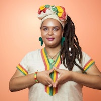 a woman with dreadlocks is making a hand gesture