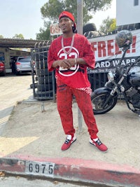 a man in red standing next to a parked car