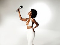 a woman holding a microphone in front of a white background