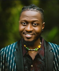 a man with dreadlocks is smiling for the camera