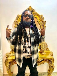 a man with dreadlocks standing in front of a gold mirror
